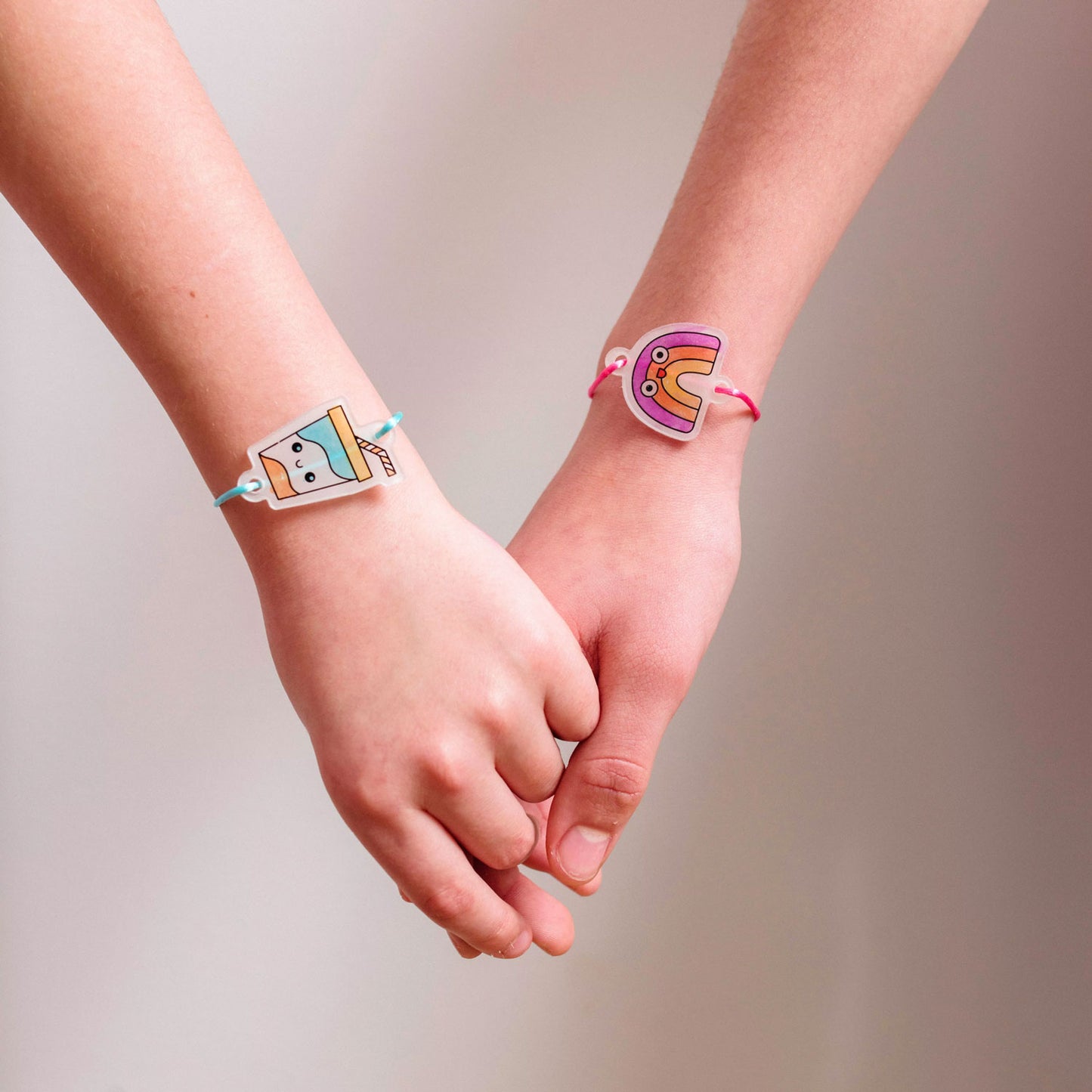 Girls hold hands wearing OOLY Shrink-its! DIY Shrink Art Kit - BFF Bracelet