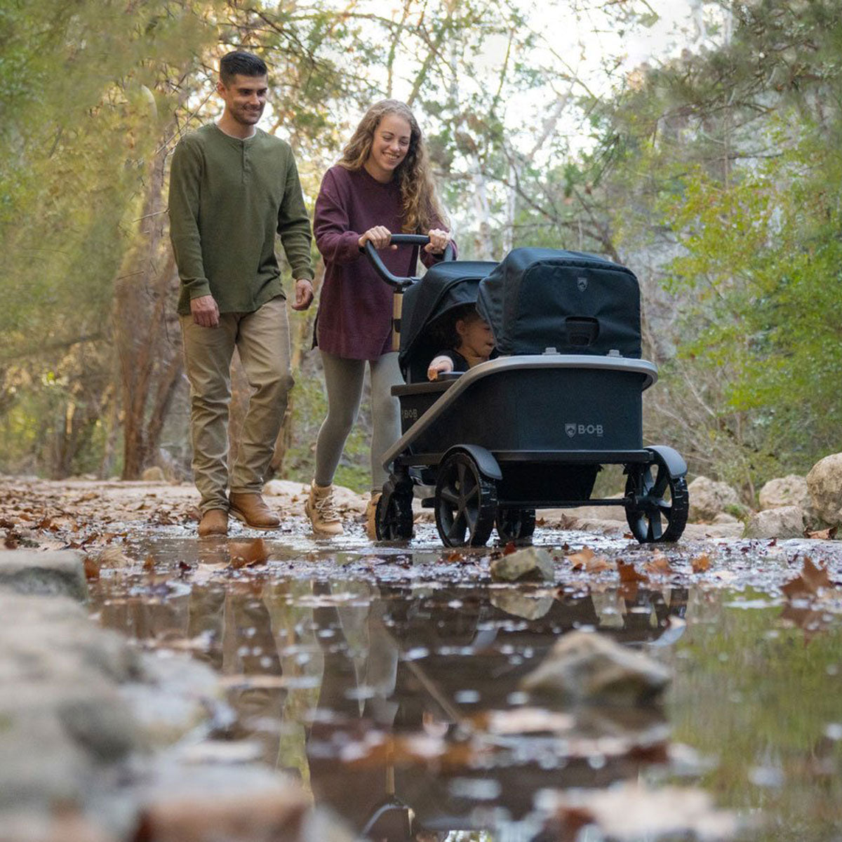 Parents pushing BOB Renegade Wagon Bundle with child inside - Nightfall with Black Canopies