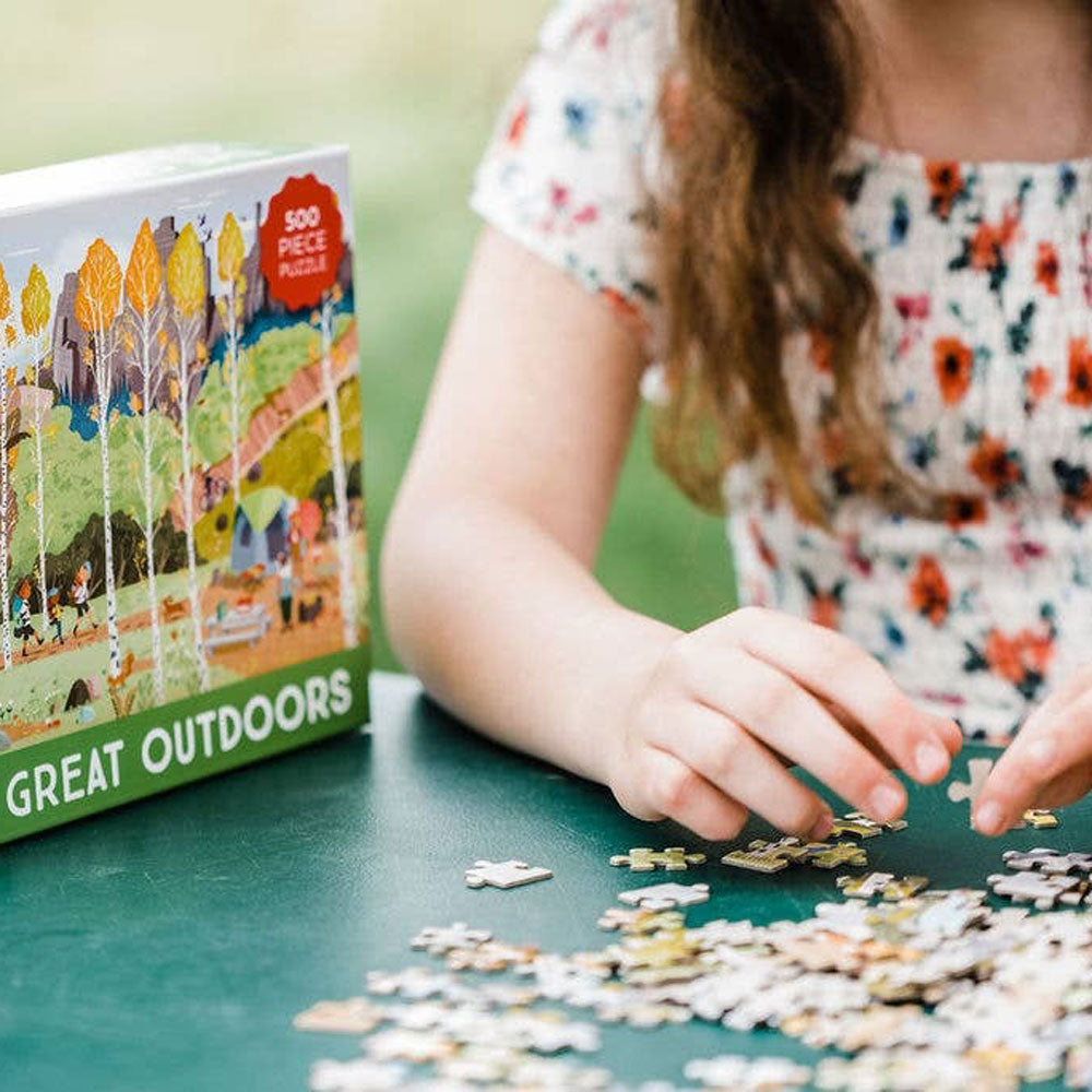 Little girl sits and puts together BabyLit The Great Outdoors Puzzle - 500 Piece