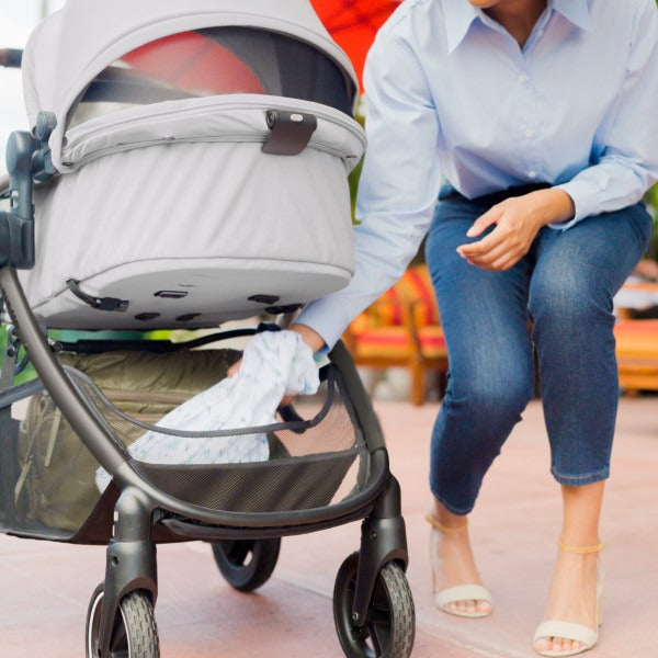 Mom grabs item out of storage basket of Maxi-Cosi Zelia2 Luxe+ 5-in-1 Travel System with Mico Luxe+ - Arctic Frost