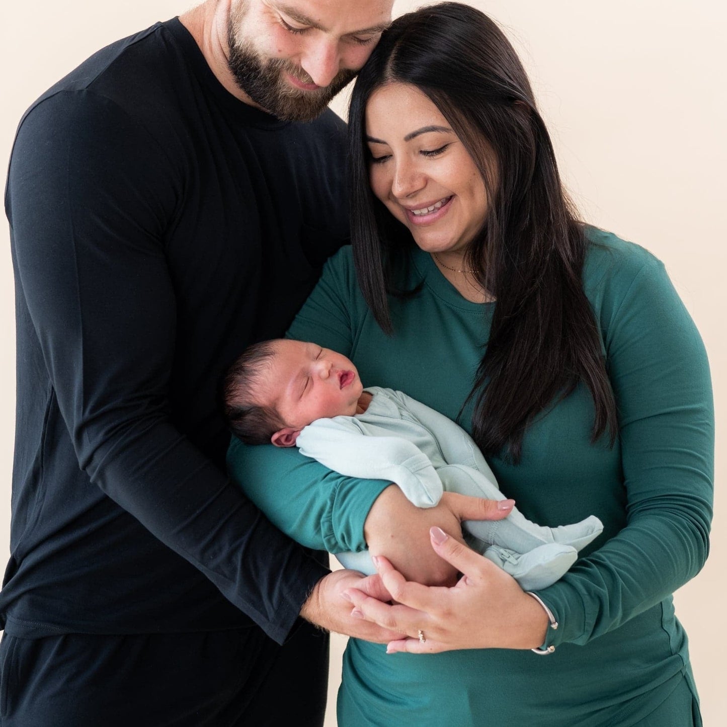 Mom and dad holding newborn baby wearing Kyte BABY Zippered Footie - Sage