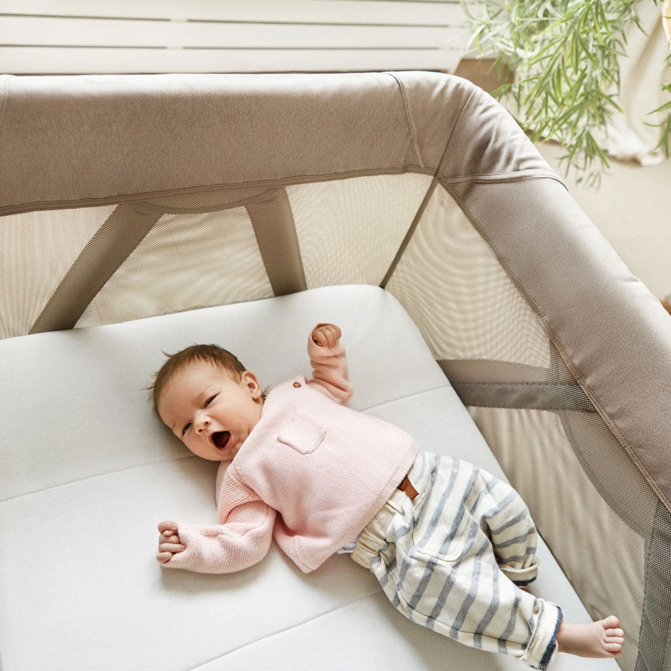 Baby laying in Nuna SENA Aire Play Yard with Zip-Off Bassinet - Hazelwood