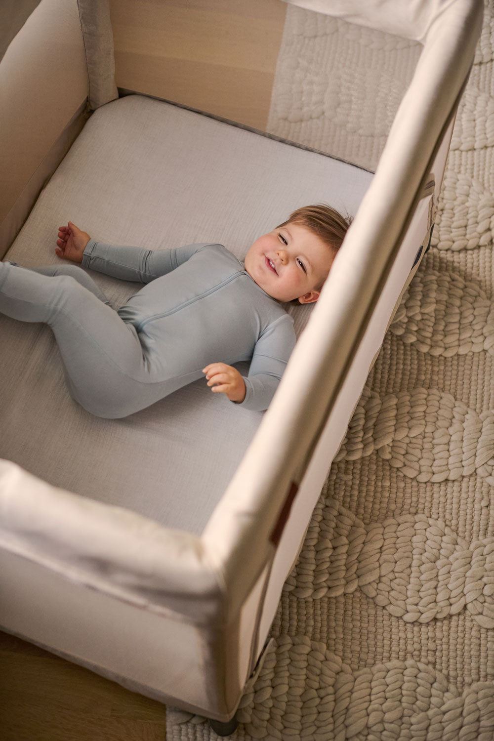 Toddler laying on UPPAbaby Organic Cotton Mattress Cover - REMI