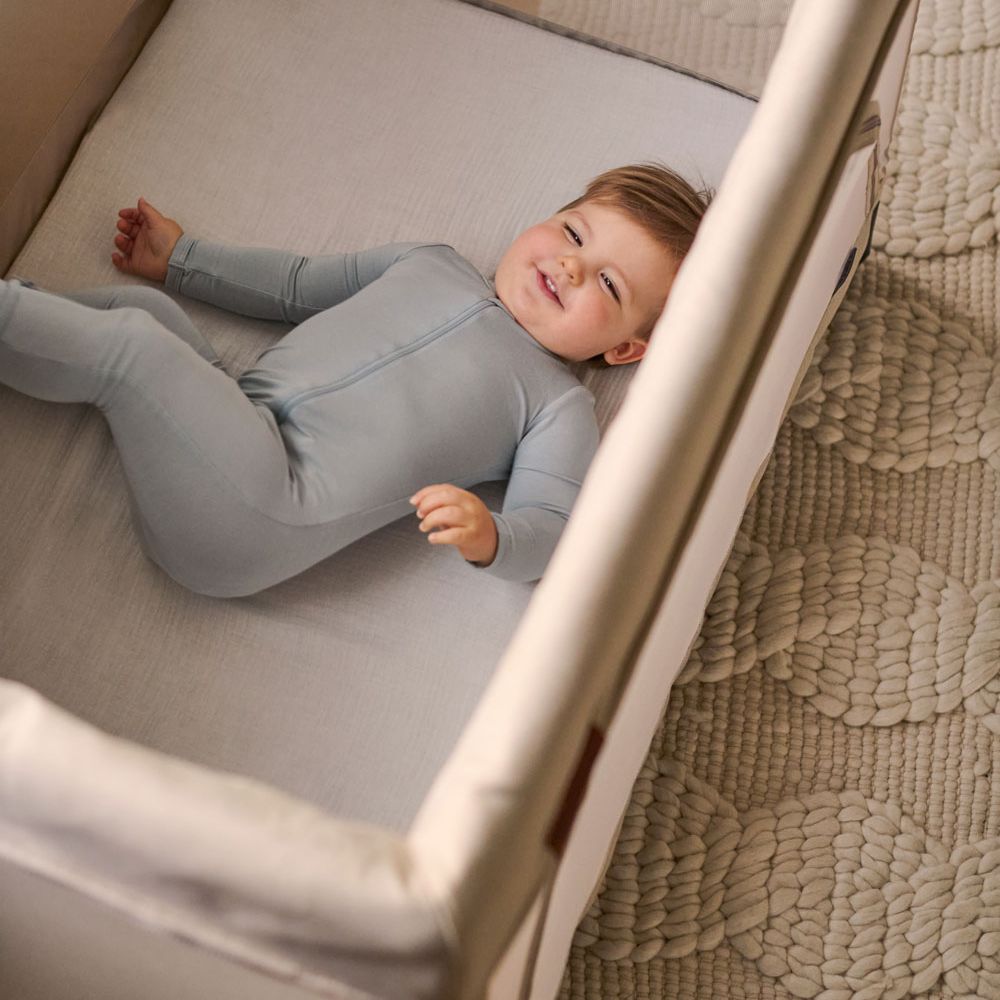 Toddler laying on UPPAbaby Organic Cotton Mattress Cover - REMI