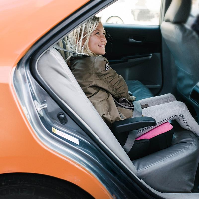 Girl sitting in Clek Olli Backless Booster Seat - Flamingo