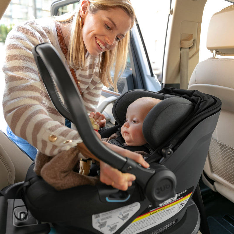 Mom adjusting handle on UPPAbaby ARIA Infant Car Seat - JAKE (Charcoal)