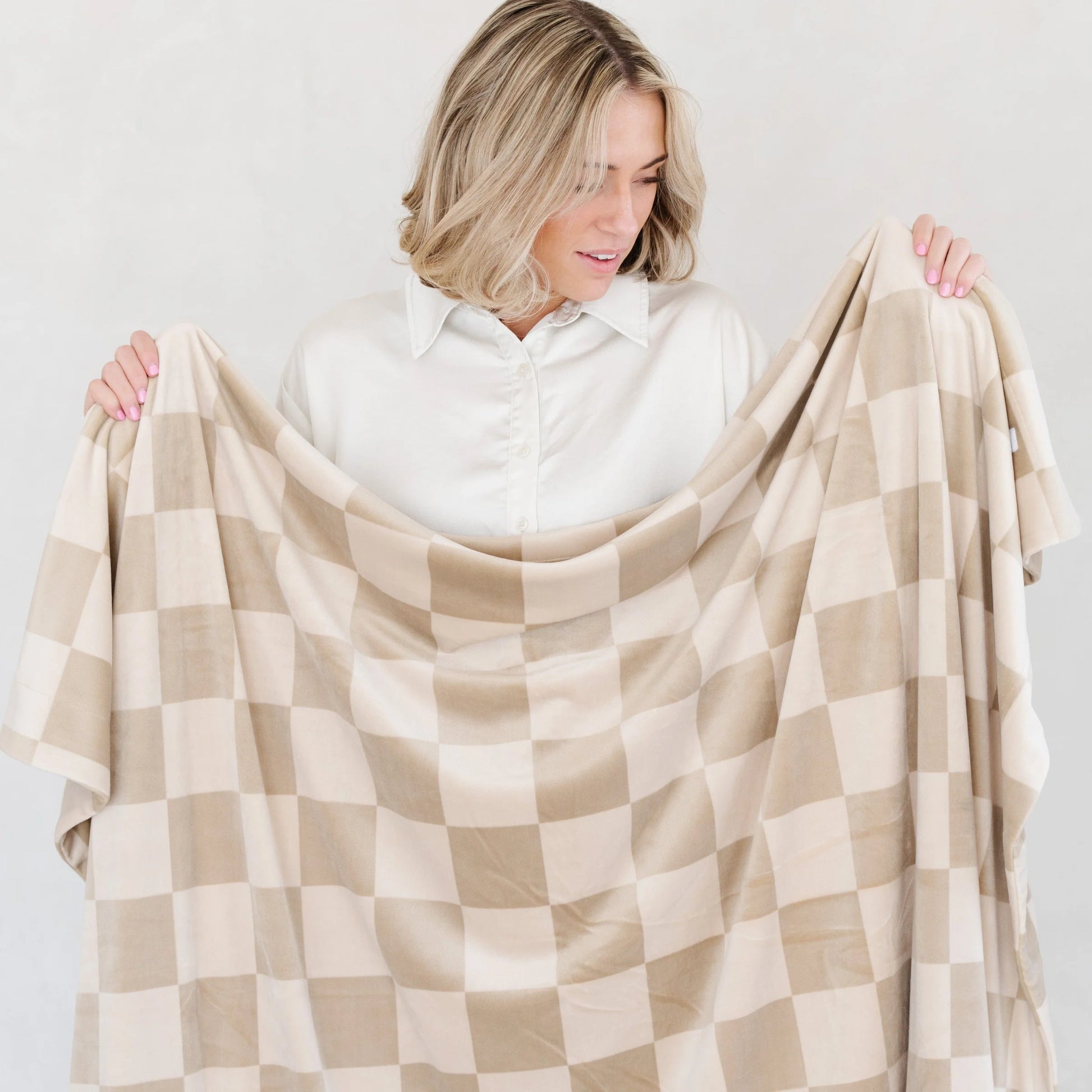 Woman holding Saranoni Minky Stretch Throw Blanket - Neutral Checkered