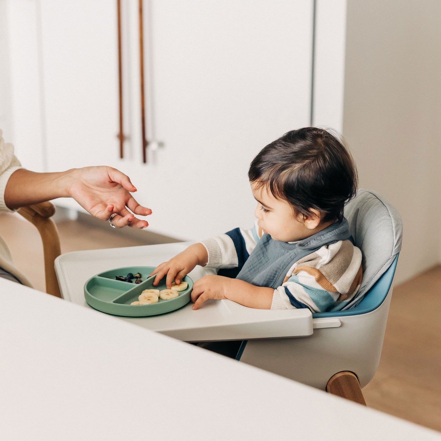 Baby eating snacks while sitting on UPPAbaby CIRO High Chair Seat Cushion in UPPAbaby CIRO High Chair - CALEB (Steel Blue)