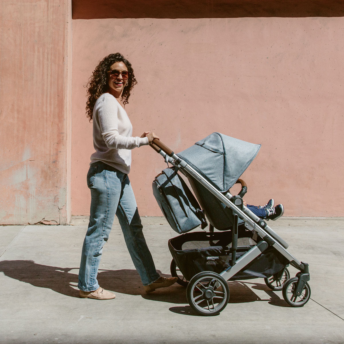 Woman pushes stroller with UPPAbaby Changing Backpack
