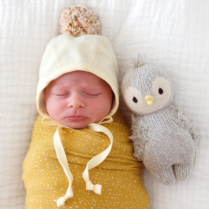 Baby lying next to Cuddle and Kind Baby Penguin - Grey