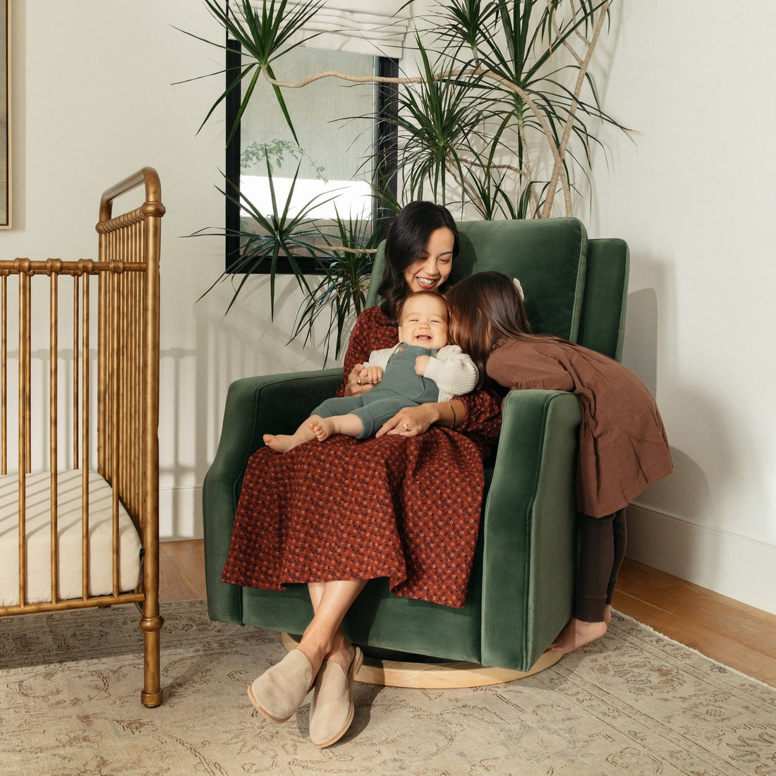 Mother and Children sitting in Namesake Crewe Recliner and Swivel Glider - Forest Green Velvet with Light Wood Base
