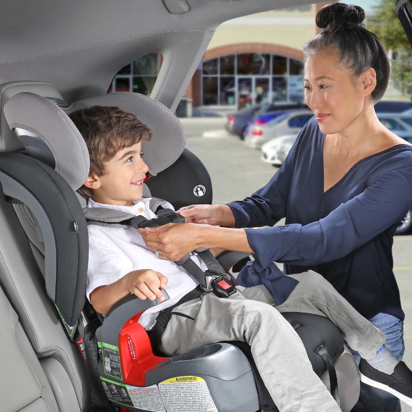 Mom buckling child into a Britax Grow With You ClickTight Harness-2-Booster Seat in back seat of car