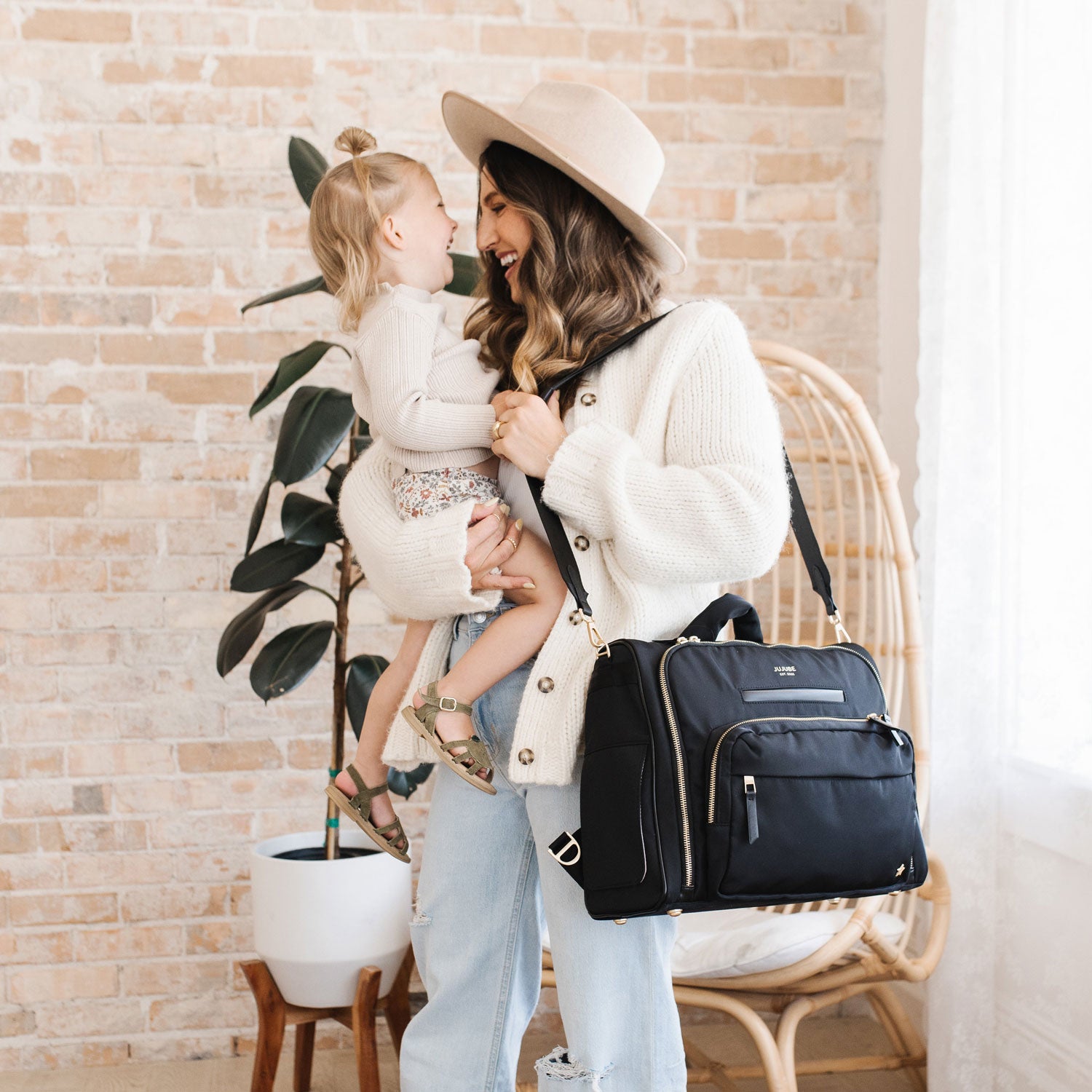 Mom smiles at toddler with JuJuBe Satchel - Black on her shoulder