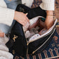 Mom organizes baby's things inside of JuJuBe Satchel - Black