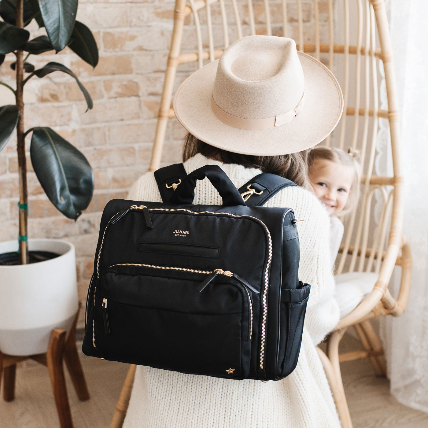 Mom carries JuJuBe Satchel - Black on her back