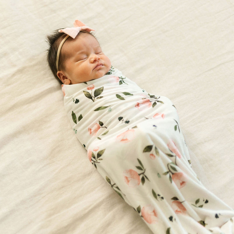 Baby wrapped in Little Unicorn Stretch Knit Swaddle Blanket - Watercolor Roses