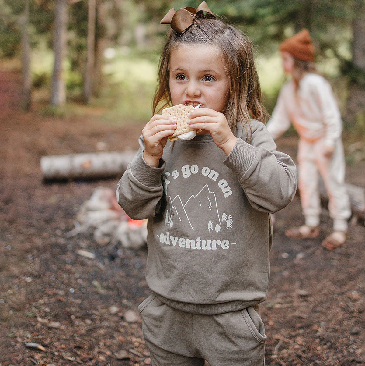 Little girl eating smores while camping wearing Mebie Baby French Terry Set - Adventure