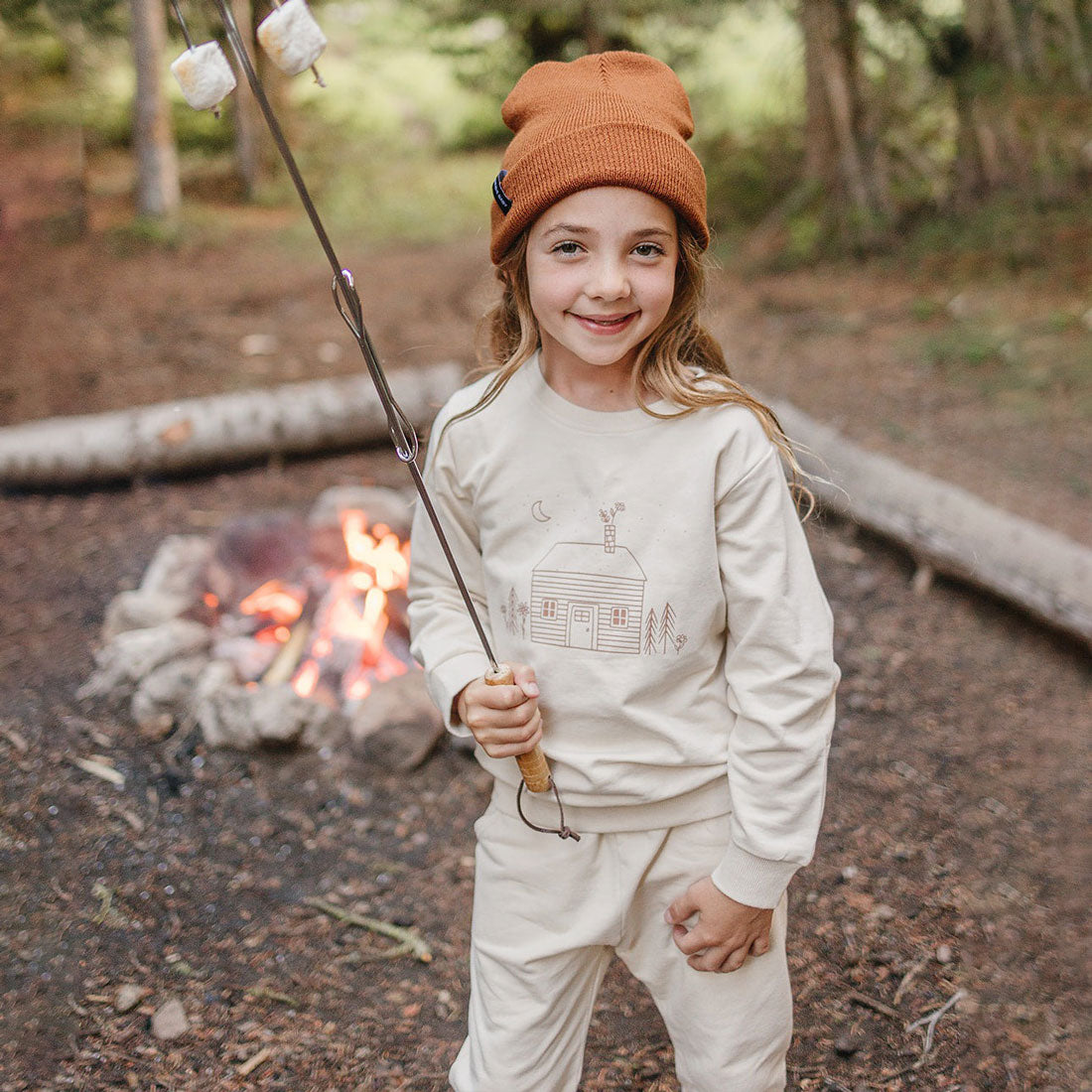 Little girl making smores at campsite while wearing Mebie Baby French Terry Set - Cabin