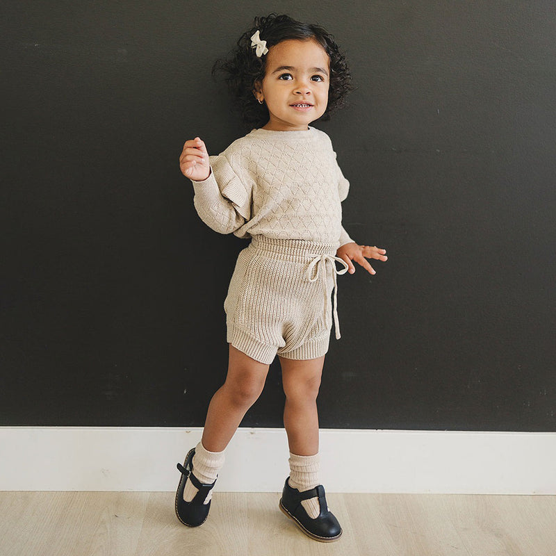 Little girl wearing Mebie Baby Knit Ruffle Sweater - Oatmeal