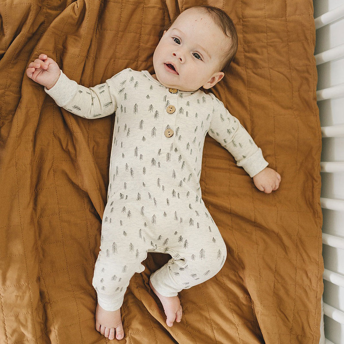 Baby lying in crib wearing Mebie Baby Romper - Pines