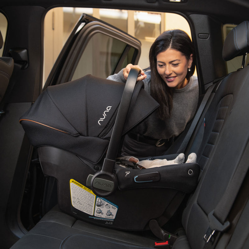 Mom installing car seat from Nuna TRVL LX Stoller and PIPA Urbn Car Seat Travel System - Caviar