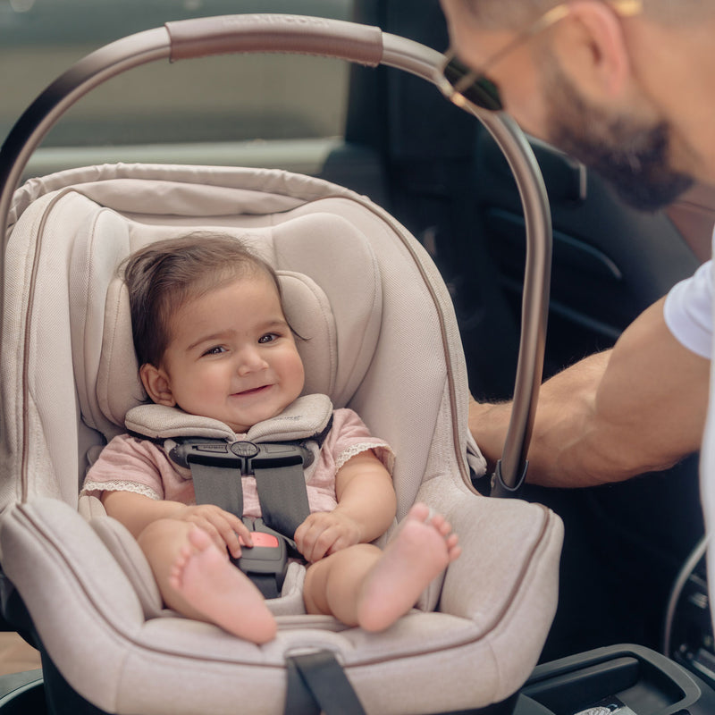Dad smiling at baby sitting in Maxi-Cosi Peri 180 Rotating Infant Car Seat - Desert Wonder