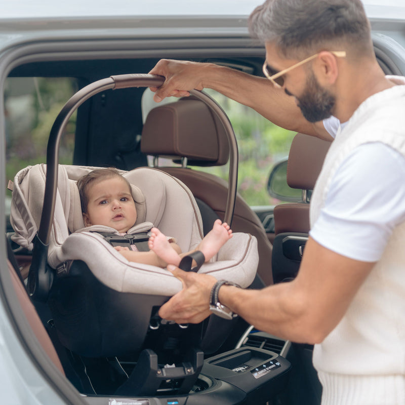 Dad placing Maxi-Cosi Peri 180 Rotating Infant Car Seat - Desert Wonder into car