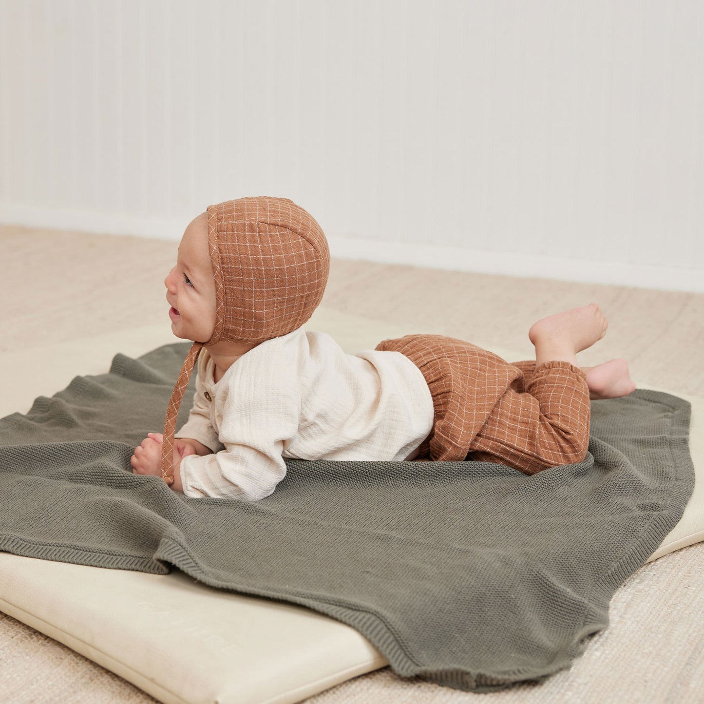 Baby sitting on Quincy Mae Knit Baby Blanket - Forest