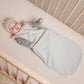 Baby lying in crib wearing Quincy Mae Jersey Sleeping Bag - Dusty Blue Stripe