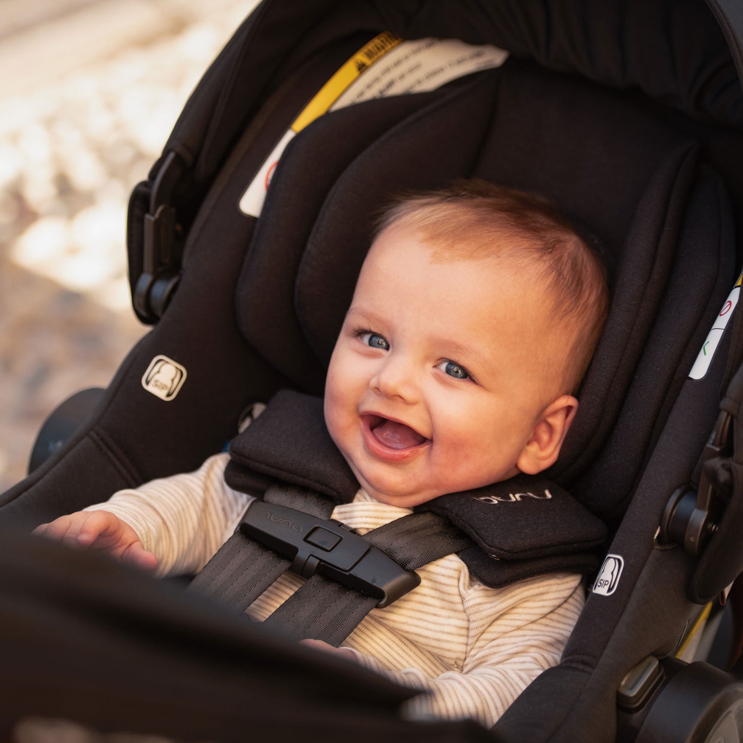 Baby smiles while riding in Nuna TRVL LX Stoller and PIPA Urbn Car Seat Travel System - Caviar