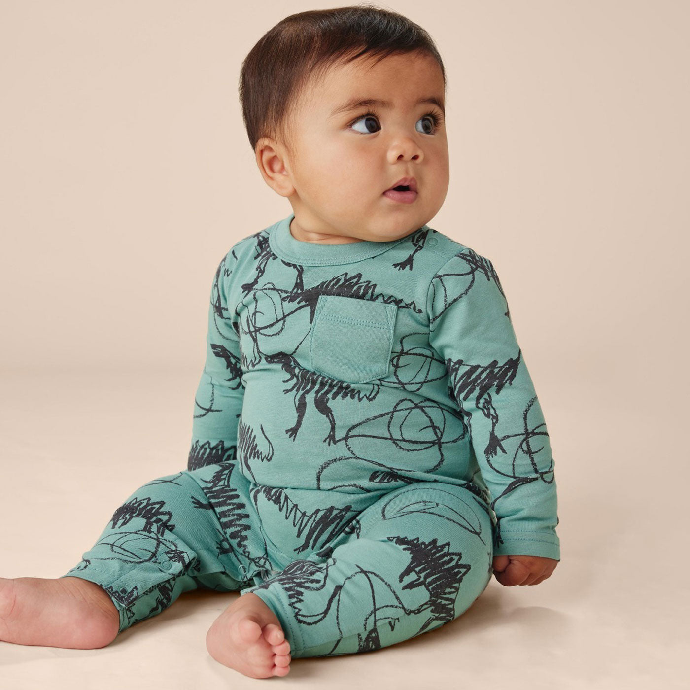 Baby wearing Tea Collection Long Sleeve Pocket Baby Romper - Scribbled Dinosaurs