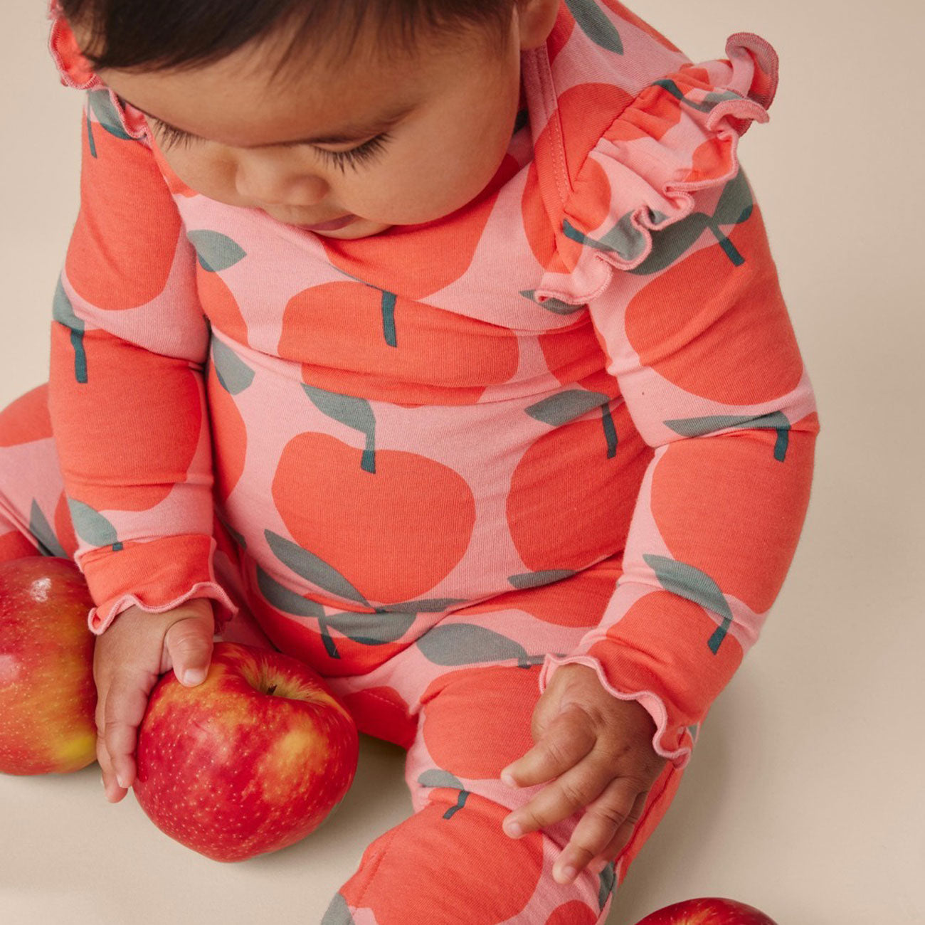 Baby wearing Tea Collection Ruffle Shoulder Baby Romper - Normandy Apples