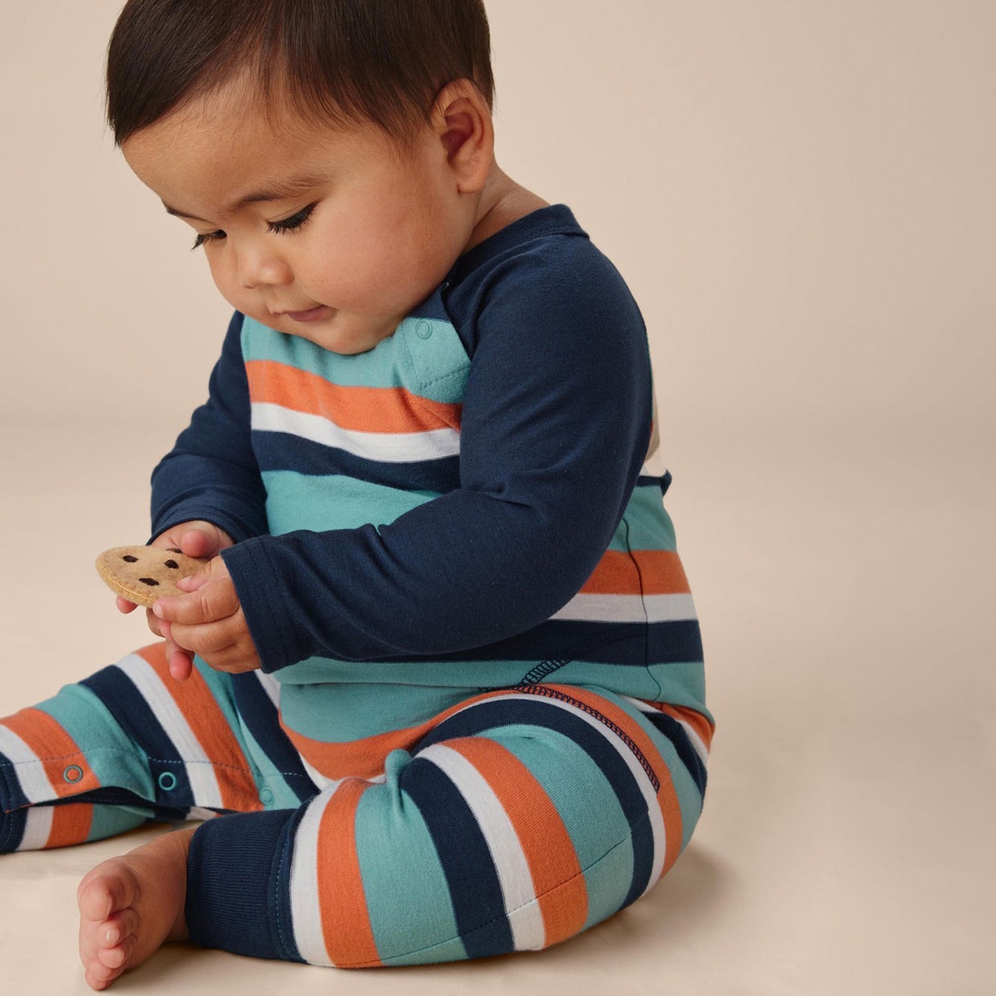 Baby plays with toy while wearing Tea Collection Striped Raglan Romper - Seaspray