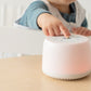 Toddler pressing button on Dreamland Baby Dream Sound Machine - White