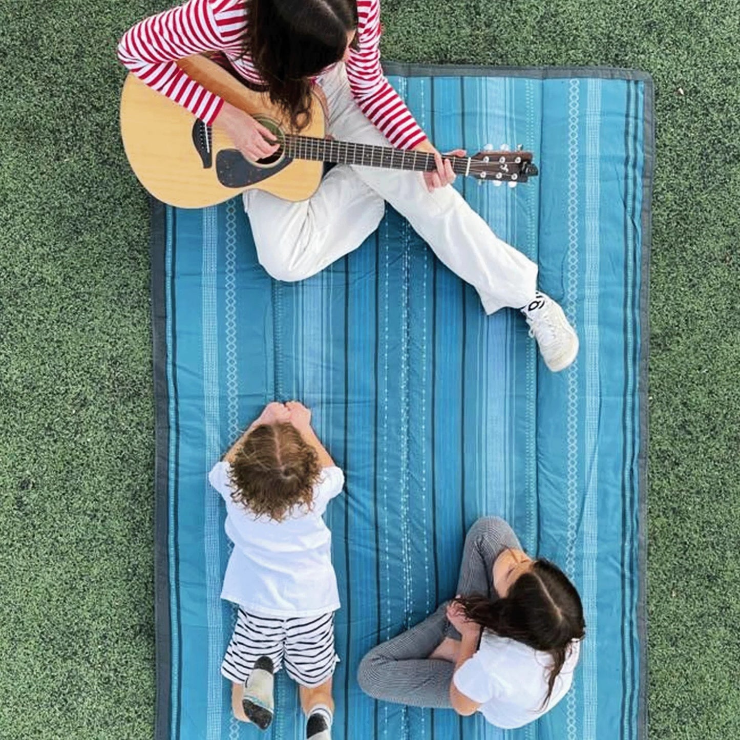 Family sits on Little Unicorn Outdoor Blanket - 5x10