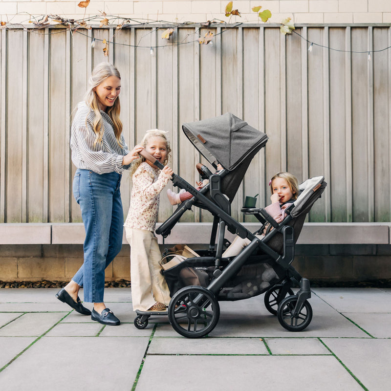 Mom pushes three children in UPPAbaby VISTA stroller with UPPAbaby VISTA V2 RumbleSeat V2+ - GREYSON (Charcoal Melange) attached