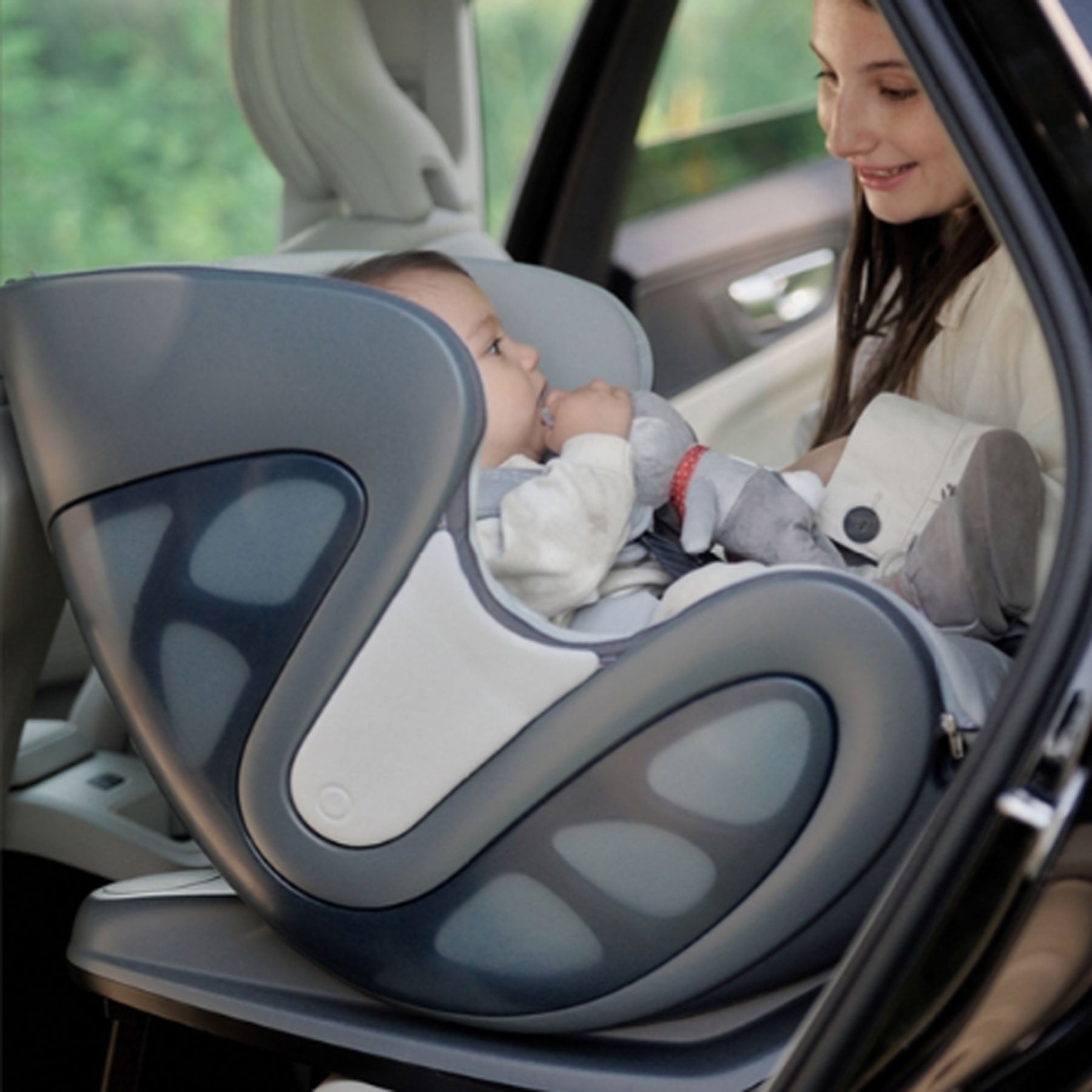 Mom sitting next to baby in babyark Convertible Car Seat + Base - Glacier Ice Seat / Charcoal Grey Base