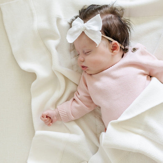 Baby lying on Saranoni Heirloom Cotton Knit Receiving Blanket - Cream