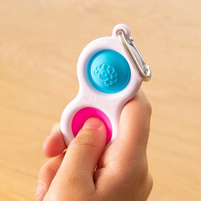Hand pressing Fat Brain Toys Simpl Dimpl Clip - Bule / Pink