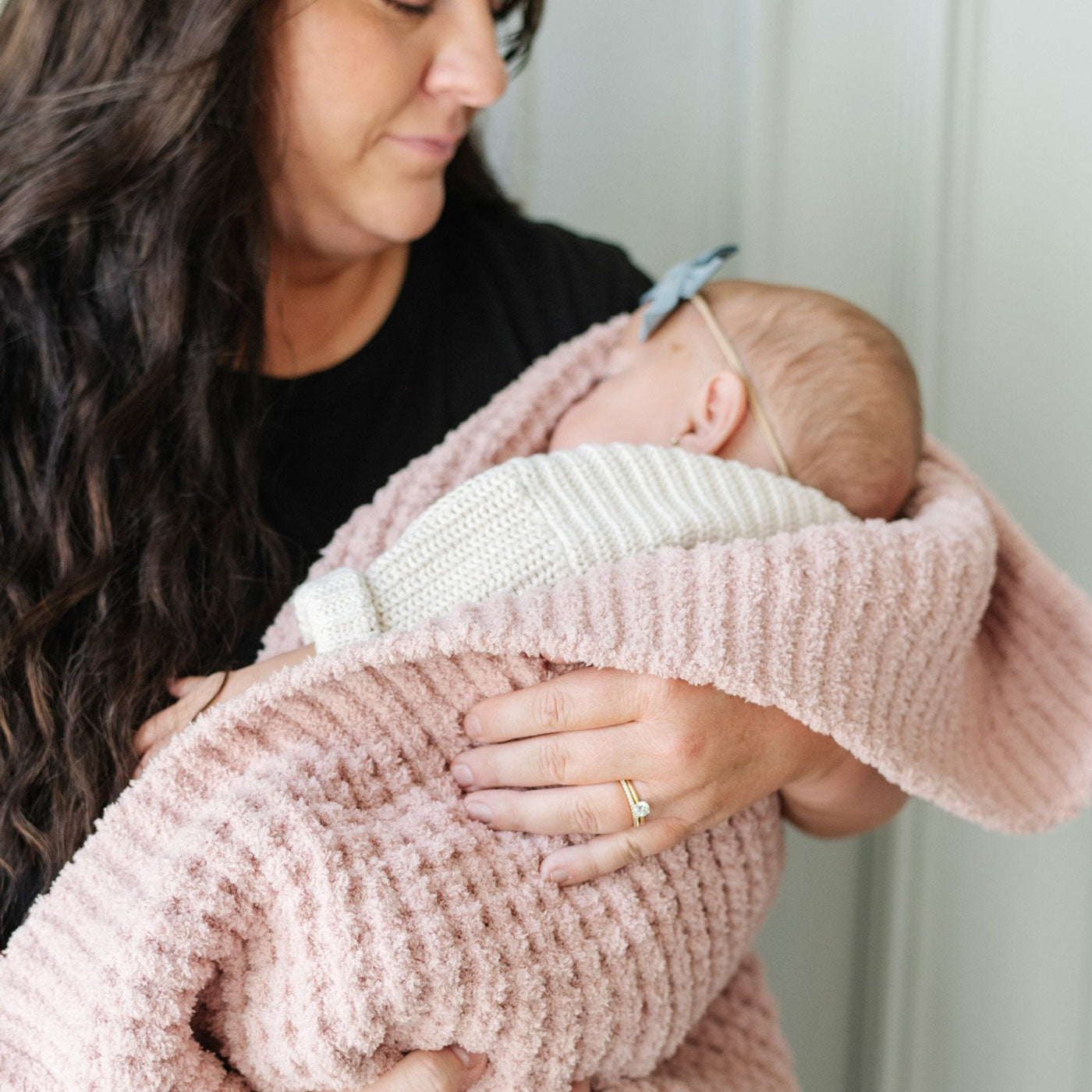 Mom holds sleeping baby wrapped in Saranoni Receiving Waffle Knit Blanket - Rosette