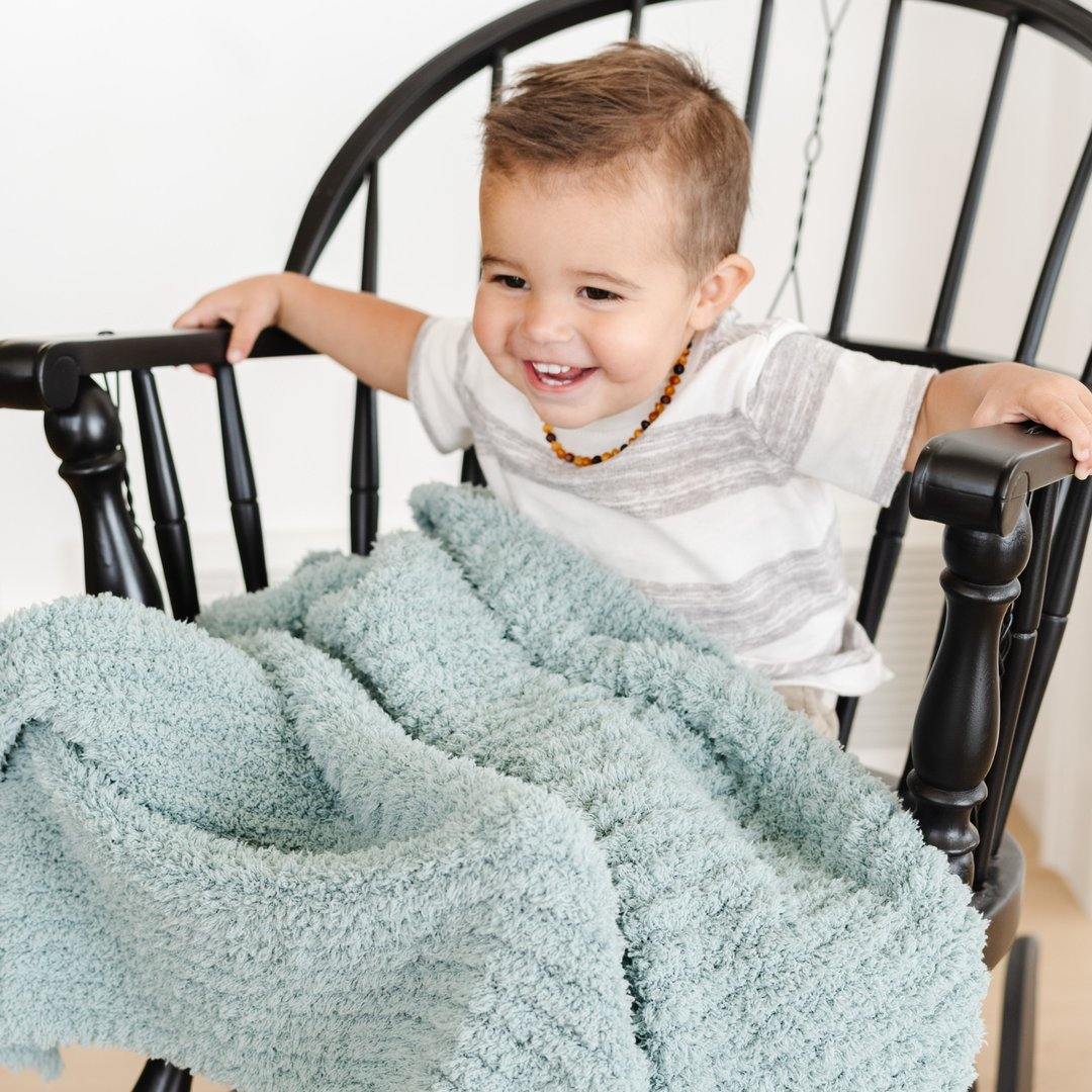 Little Boy sitting with Saranoni Receiving Ribbed Bamboni Blanket - Surf