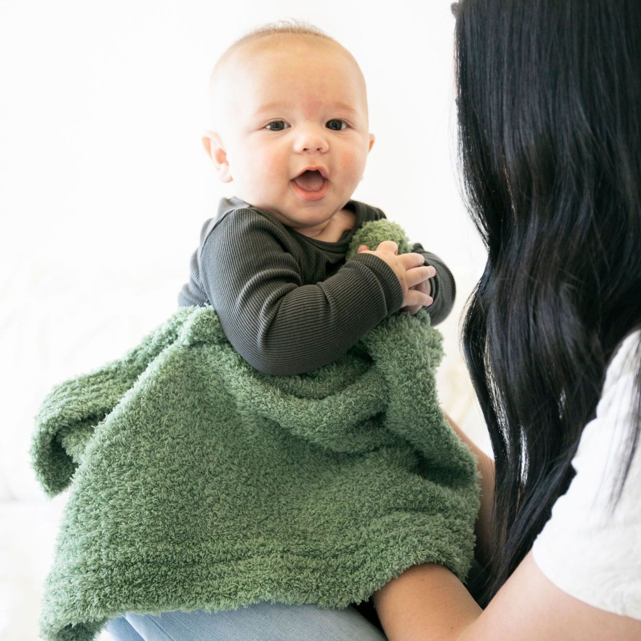 Mother holding baby in Saranoni Receiving Bamboni Blanket - Olive