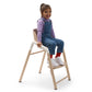 Child sits in Baby sits in Bugaboo Giraffe High Chair Complete - Neutral Wood / White
