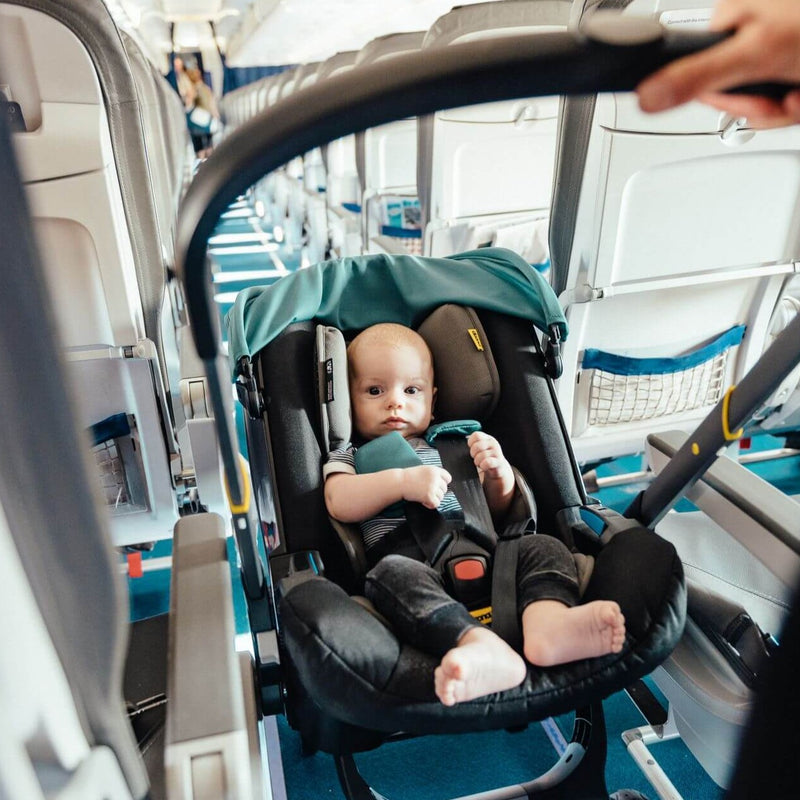 Parent pushes baby in Doona Infant Car Seat and Stroller down airplane aisle