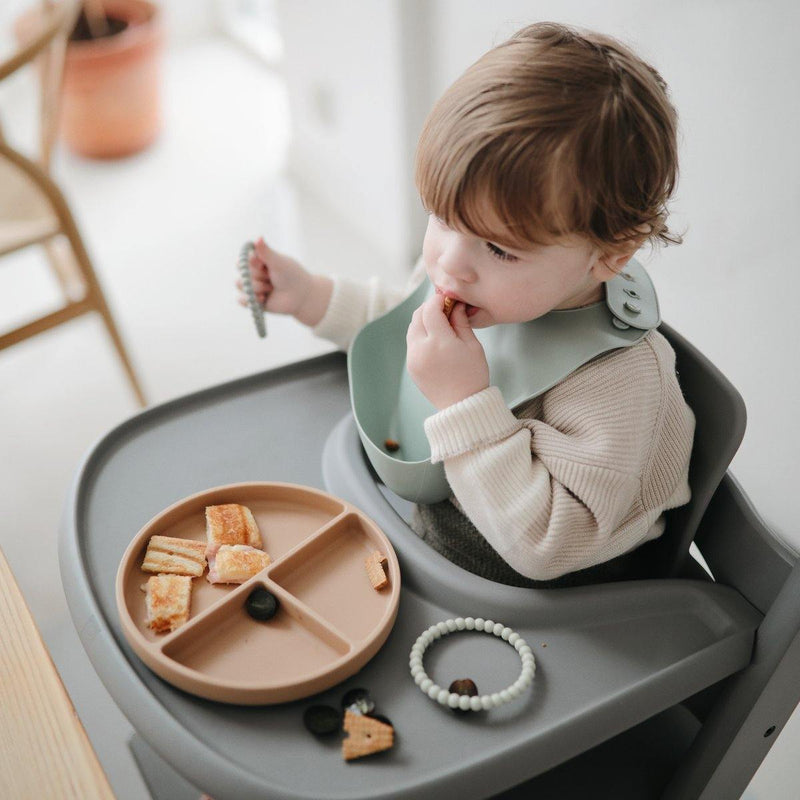 Toddler eating food from Mushie Silicone Suction Plate - Natural