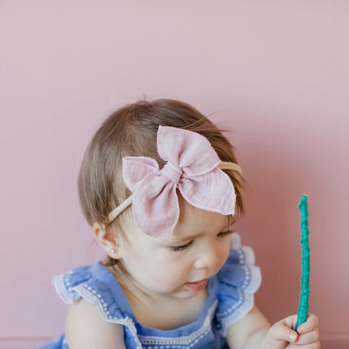 Baby girl wears Modern Piggy Gauze Petite Party Bow - Nylon Headband - Blush