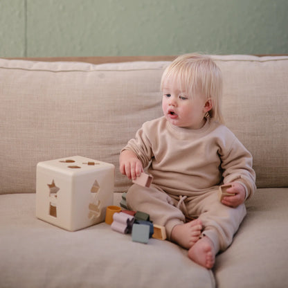 Toddler playing with Mushie Shape Sorting Box