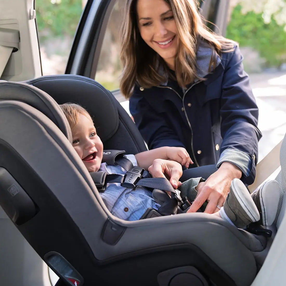 Woman buckles child in Nuna RAVA Convertible Car Seat