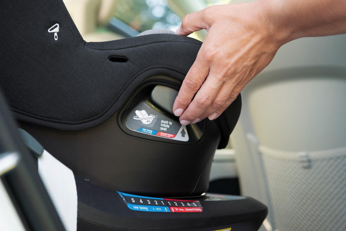 Person adjusts Nuna REVV Rotating Convertible Car Seat