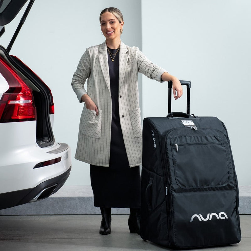 Woman standing next to car with Nuna Wheeled Travel Bag - Indigo